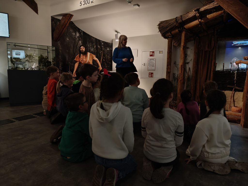 Grupa dzieci wraz z przewodnikiem podczas zwiedzania Muzeum Archeologicznego w Krakowie