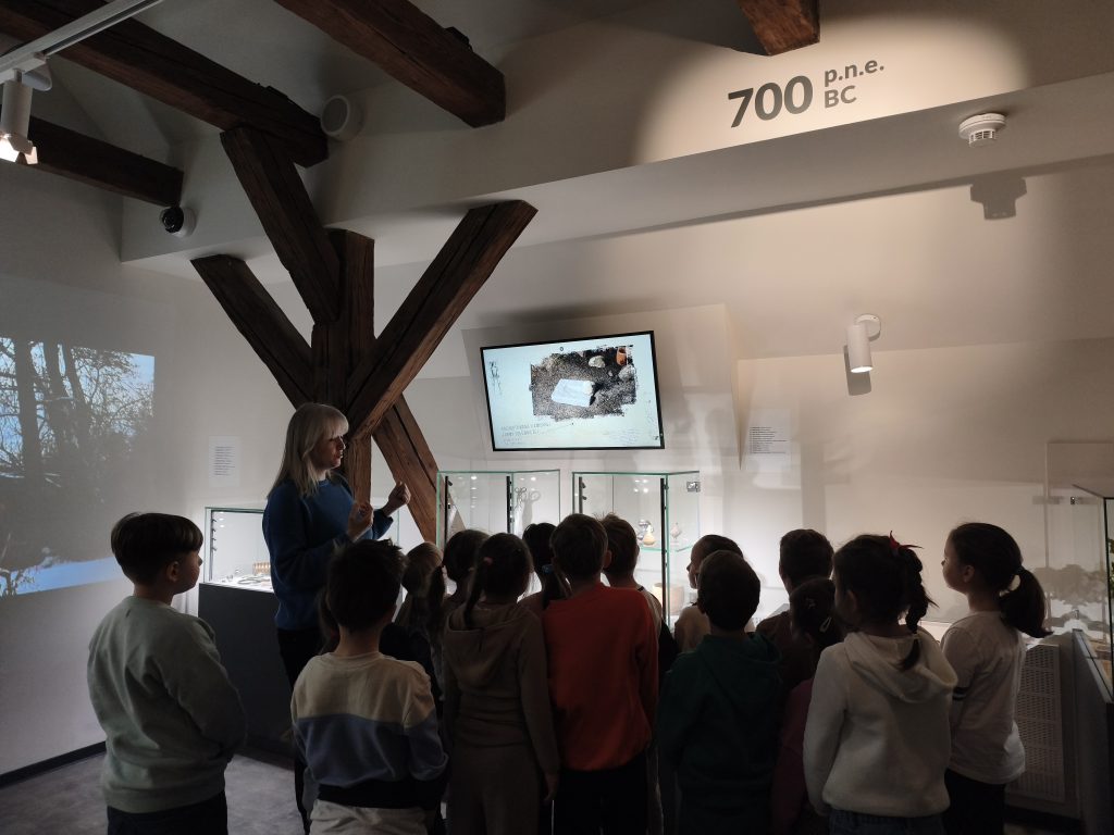 Grupa dzieci wraz z przewodnikiem podczas zwiedzania Muzeum Archeologicznego w Krakowie